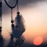 Federn eines Traumfängers mit Sonnenuntergang im Hintergrund